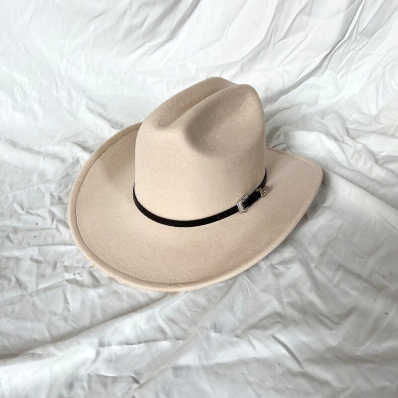Chapeau de cowboy vintage beige présenté sur un tissu blanc