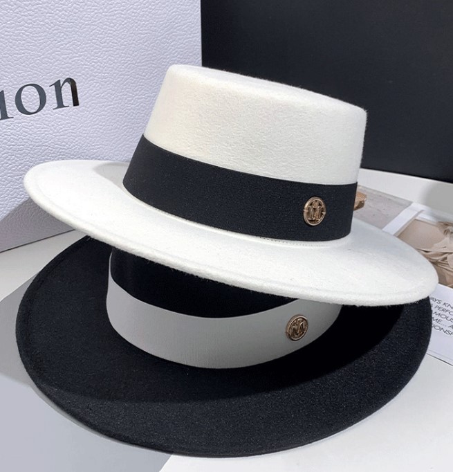 Deux chapeaux classiques sont empilés l'un sur l'autre, un noir en dessus avec ruban blanc et un blanc au-dessus avec un ruban noir