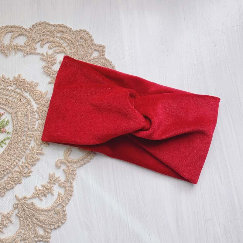 bandeau rouge en cashmere doux, posé sur un tissu blanc brodé