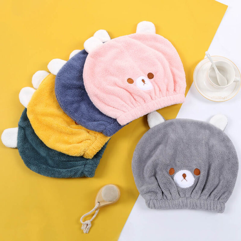 plusieurs bonnet de bain avec un design de petit ourson pour enfant, sont présentés à plat, avec différentes couleurs , un gris, un rose, puis d'autres couleurs moins visibles en dessous ; vert, gris, et jaune