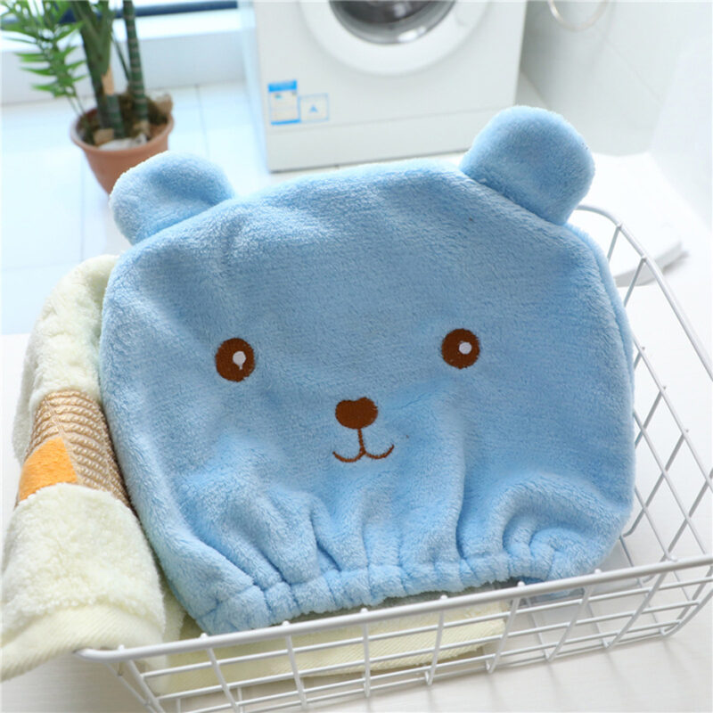 bonnet de bain présenté dans une panière de salle de bain, le bonnet est bleu et représente une tête de petit ourson mignon