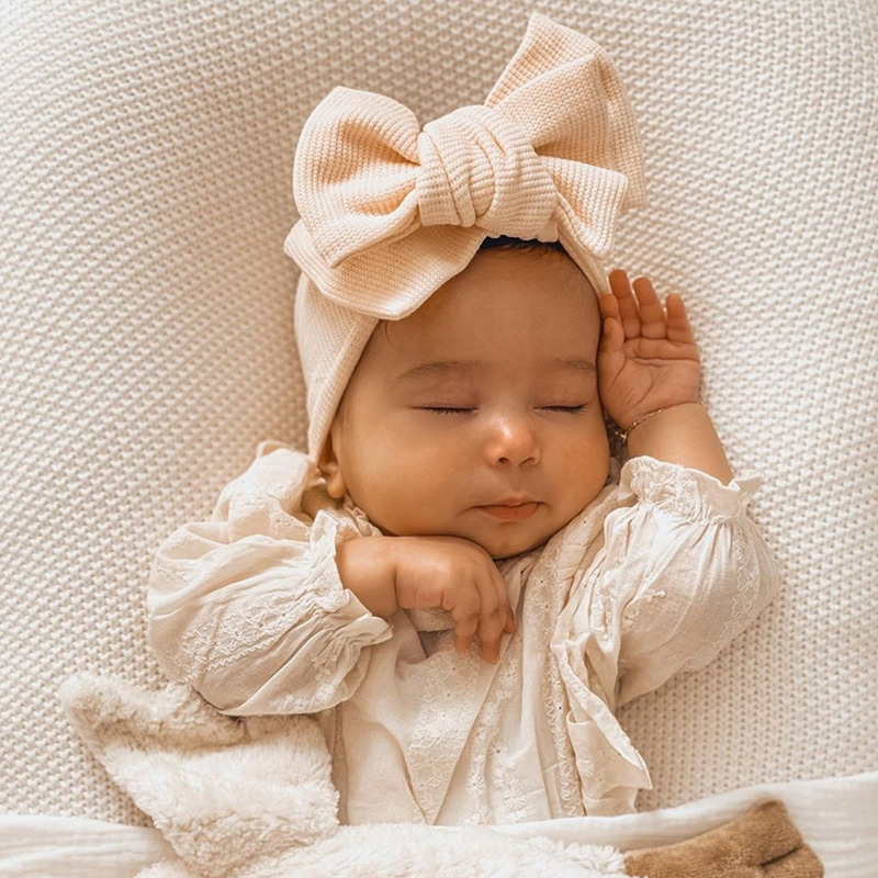 Bandeau bébé fille élastique avec nœud porté par un bébé qui dort