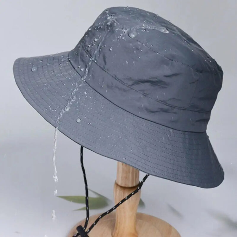 Chapeau de Pluie Femme Imperméable avec Protection Solaire posé sur un support en bois sur fond gris